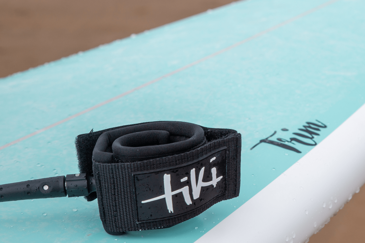 Tiki Trim surfboard close up of logo and leash 